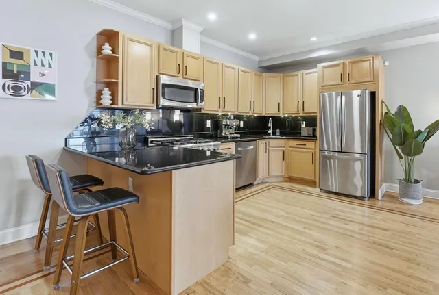 a kitchen with stainless steel appliances granite countertop a refrigerator a stove a sink dishwasher and white cabinets with wooden floor