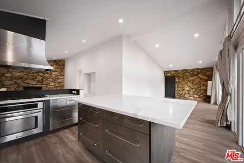an empty room with wooden floor fireplace and windows