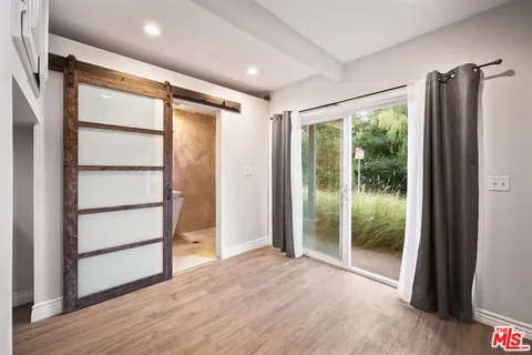 a view of an empty room with wooden floor and closet