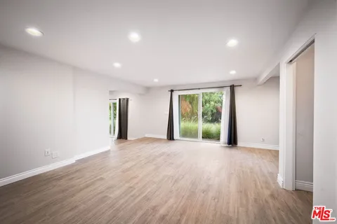 a view of an empty room with wooden floor and closet