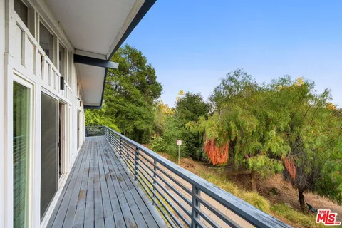 a view of a house with a big yard potted plants and large trees