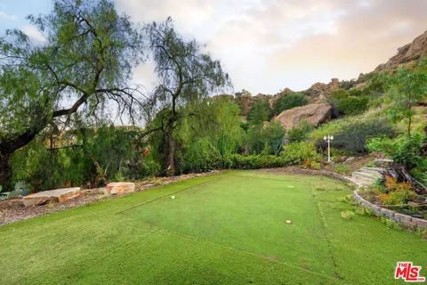 a view of a backyard with a large tree and wooden fence