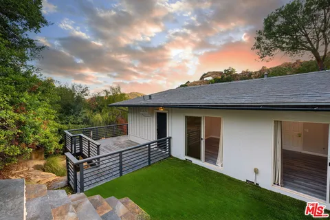 a front view of a house with a yard and potted plants