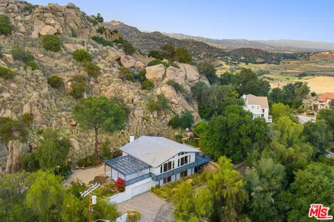 a front view of a house with a garden and lake view