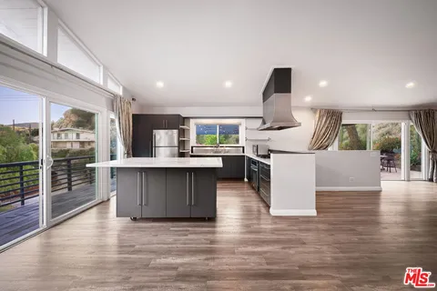 a open kitchen with stainless steel appliances kitchen island granite countertop a stove and a refrigerator