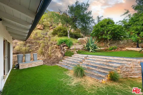 a view of a backyard with potted plants and large trees
