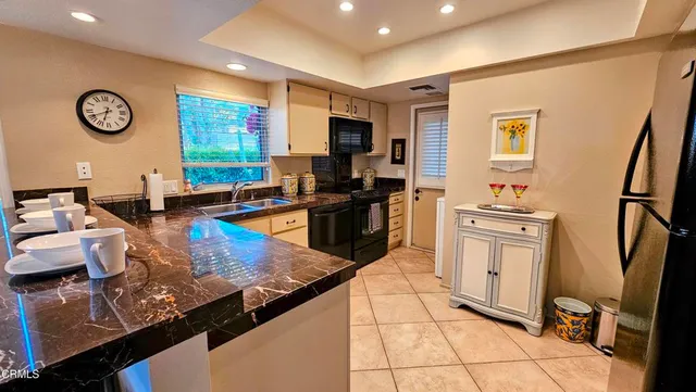 a kitchen with stainless steel appliances granite countertop a refrigerator stove top oven dining table and chairs