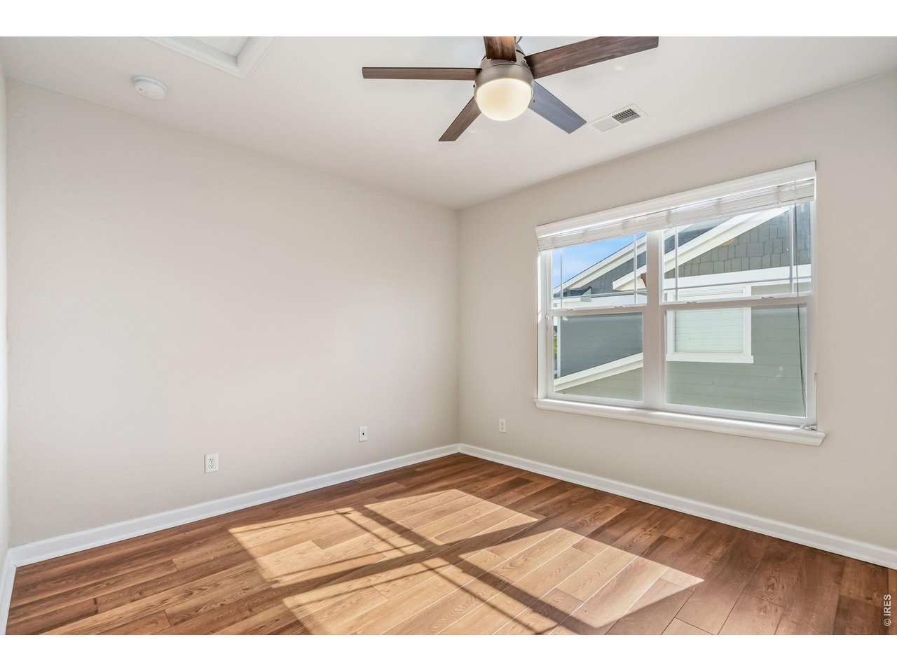 6759 Rainier Road Timnath, CO 80547 - Photo 17 of 30 an empty room with wooden floor ceiling fan and windows