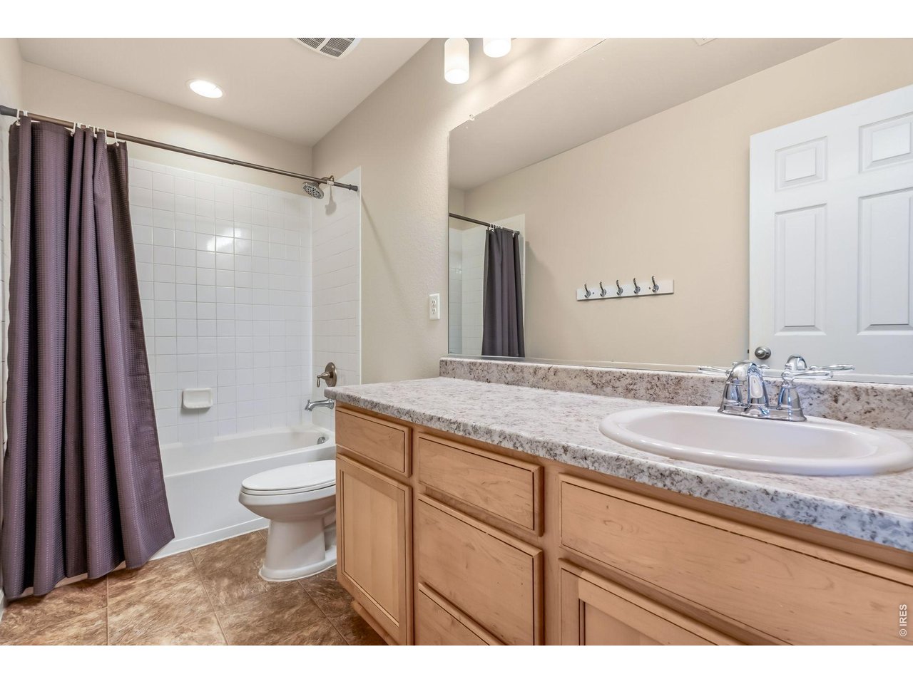 6759 Rainier Road Timnath, CO 80547 - Photo 18 of 30 a bathroom with a granite countertop sink a toilet a mirror and shower
