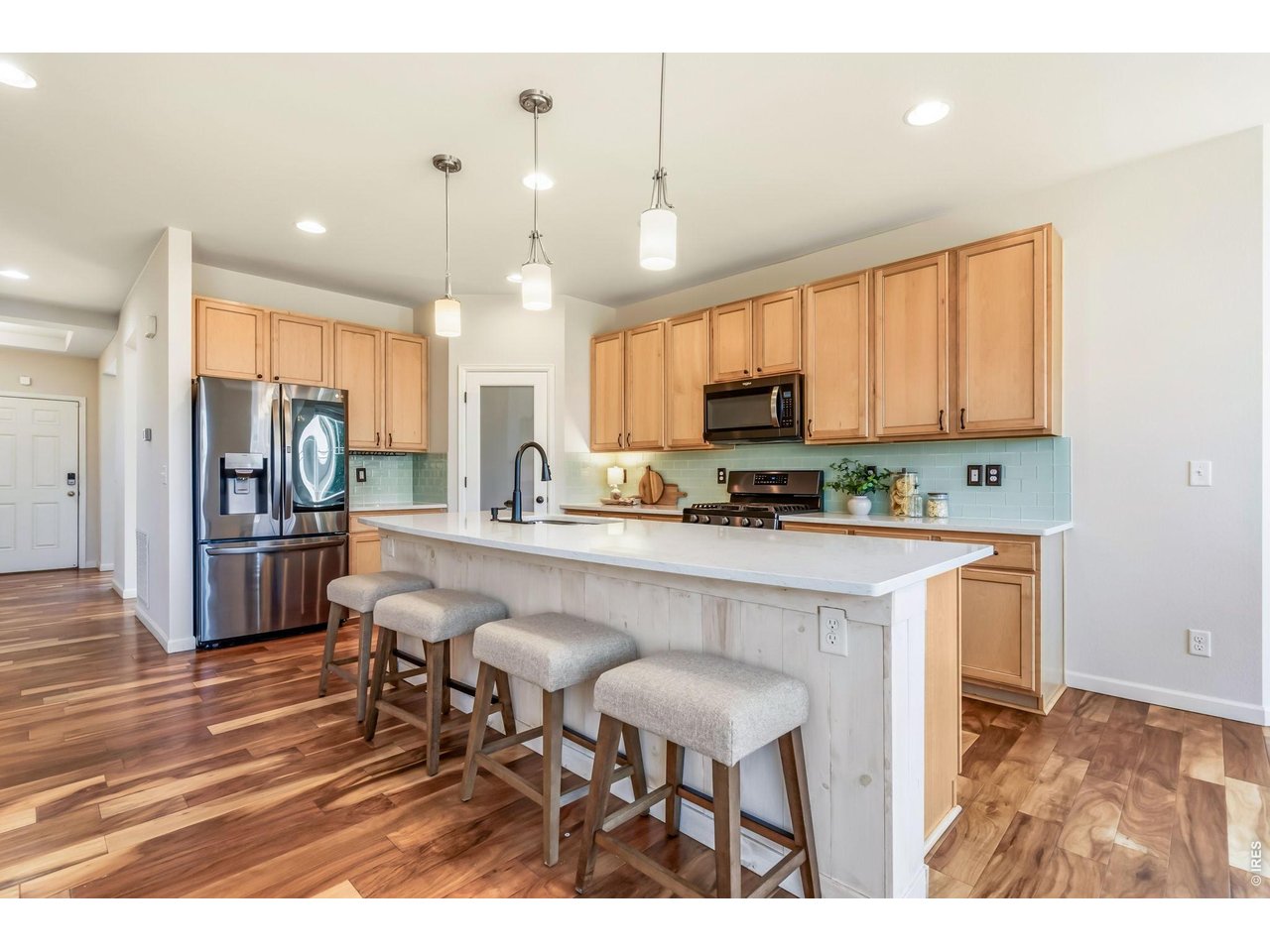 6759 Rainier Road Timnath, CO 80547 - Photo 4 of 30 a kitchen with kitchen island granite countertop wooden floors cabinets and stainless steel appliances