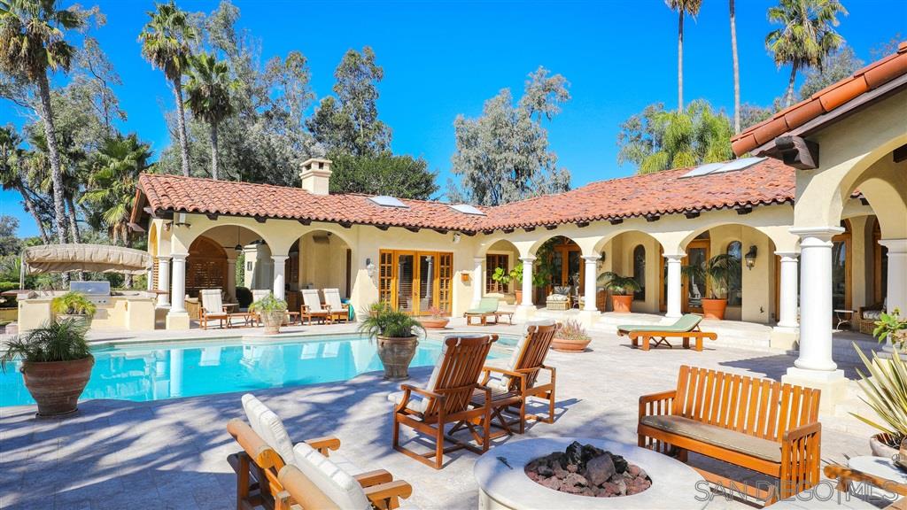 16556 Los Barbos Rancho Santa Fe, CA 92067 - Photo 19 of 22 a view of a patio with couches table and chairs potted plants and palm tree