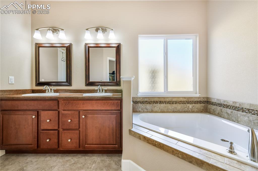 10484 Mile Post Loop Fountain, CO 80817 - Photo 23 of 50 a bathroom with a tub a double vanity sink and a large mirror