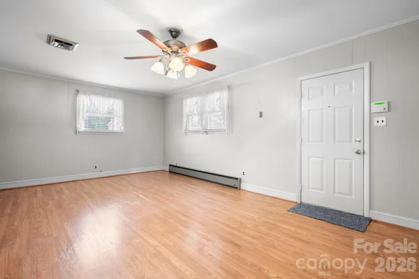 a view of an empty room with wooden floor and a window