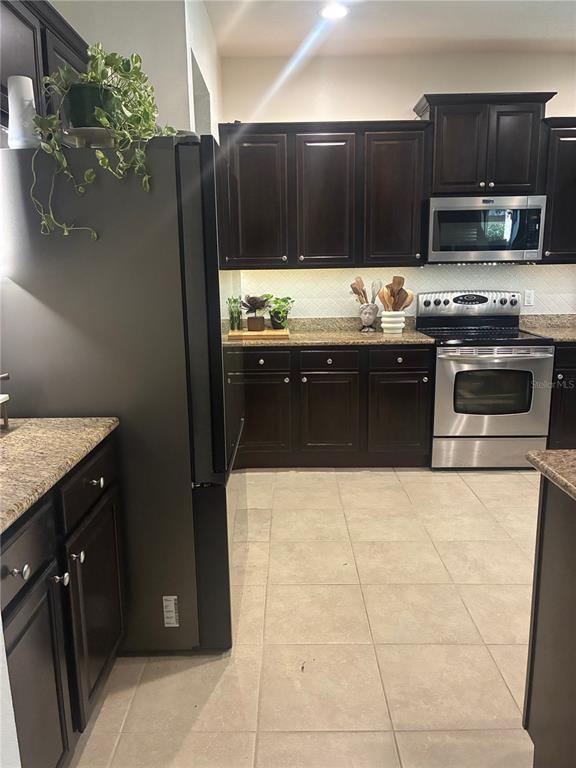 960 Seburn Road Apopka, FL 32703 - Photo 6 of 13 a kitchen with granite countertop a refrigerator and a stove top oven