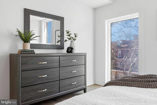 a bedroom with a bed and a potted plant on dresser