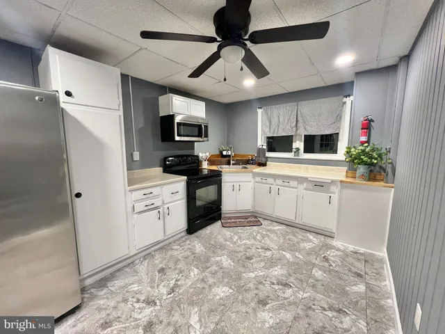 a kitchen with granite countertop a sink cabinets stainless steel appliances and a window