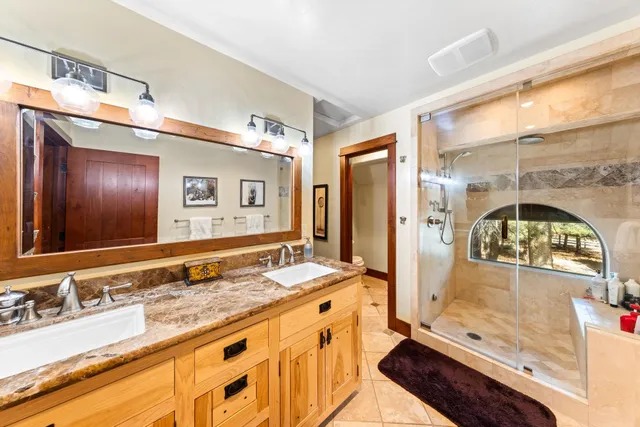 a bathroom with a double vanity sink and mirror with shower