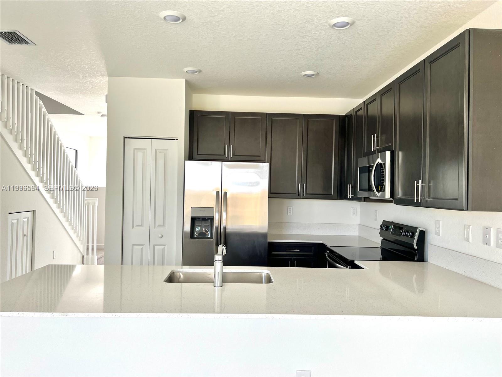 23373 Southwest 129th Path, Unit 23373 Homestead, FL 33032 - Photo 8 of 18 a kitchen with stainless steel appliances kitchen island granite countertop a refrigerator and a sink