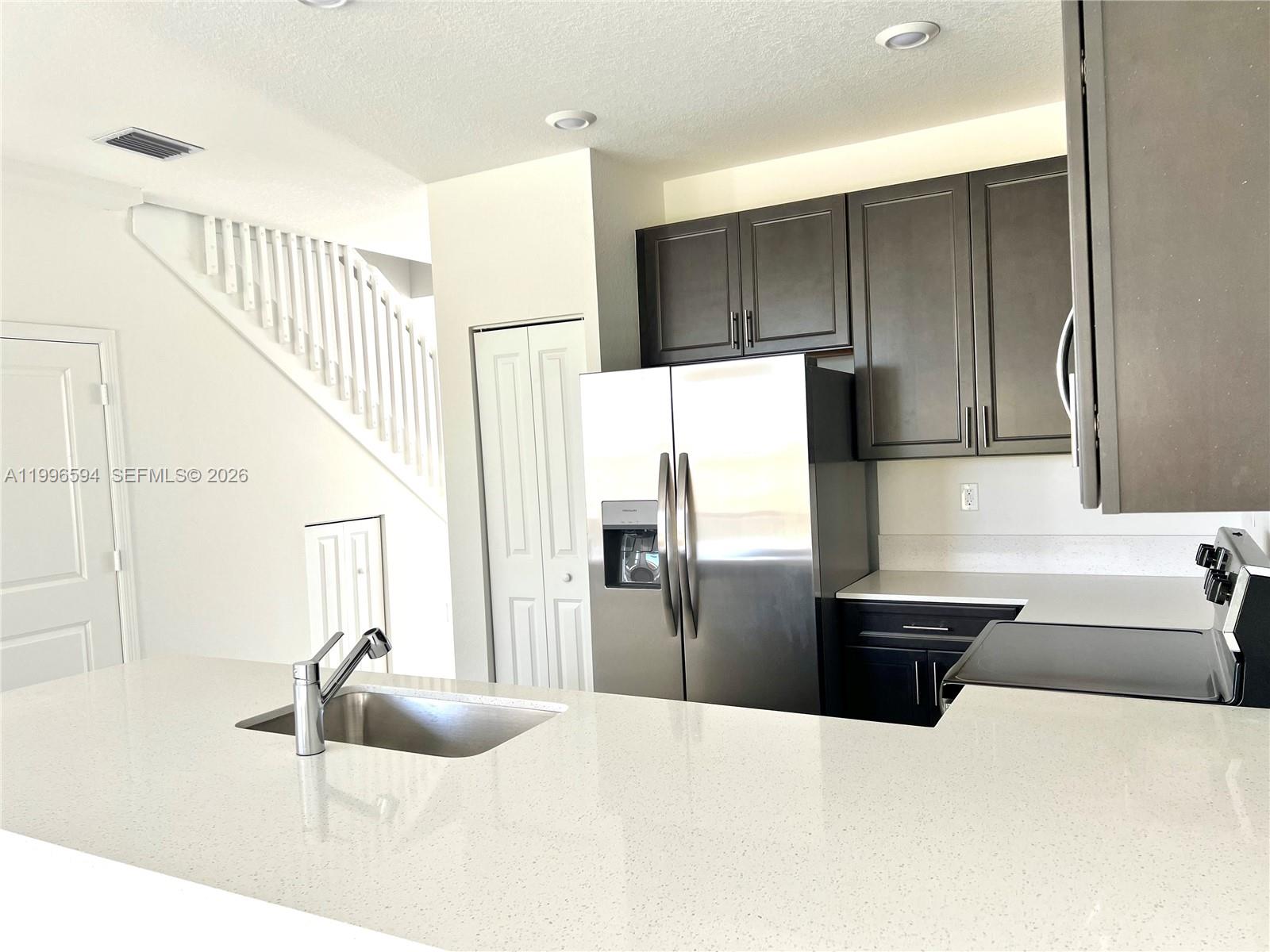 23373 Southwest 129th Path, Unit 23373 Homestead, FL 33032 - Photo 10 of 18 a kitchen with stainless steel appliances kitchen island granite countertop a sink and refrigerator