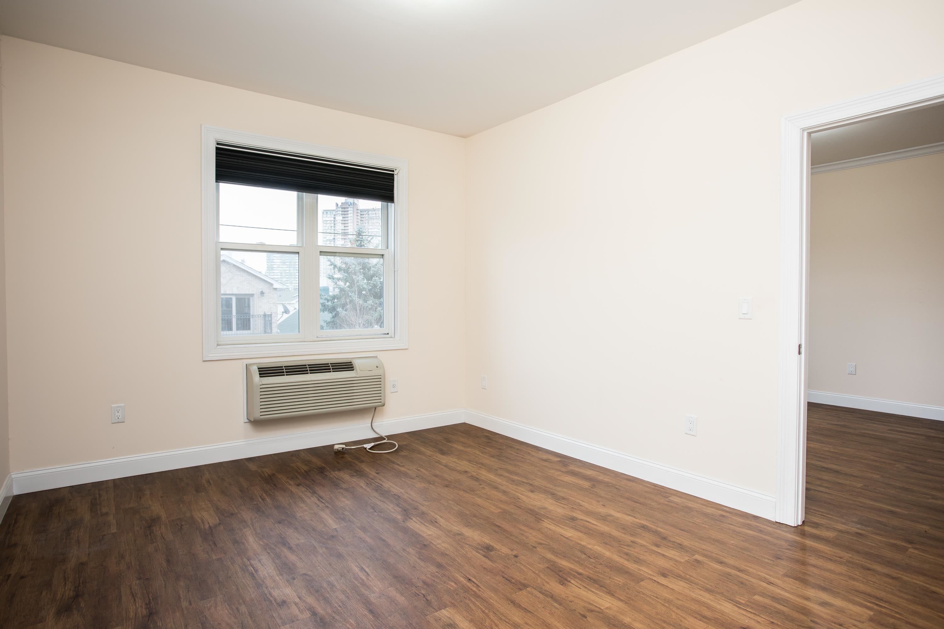 6111 Fillmore Place, Unit 306 West New York, NJ 07093 - Photo 11 of 27 an empty room with wooden floor and windows