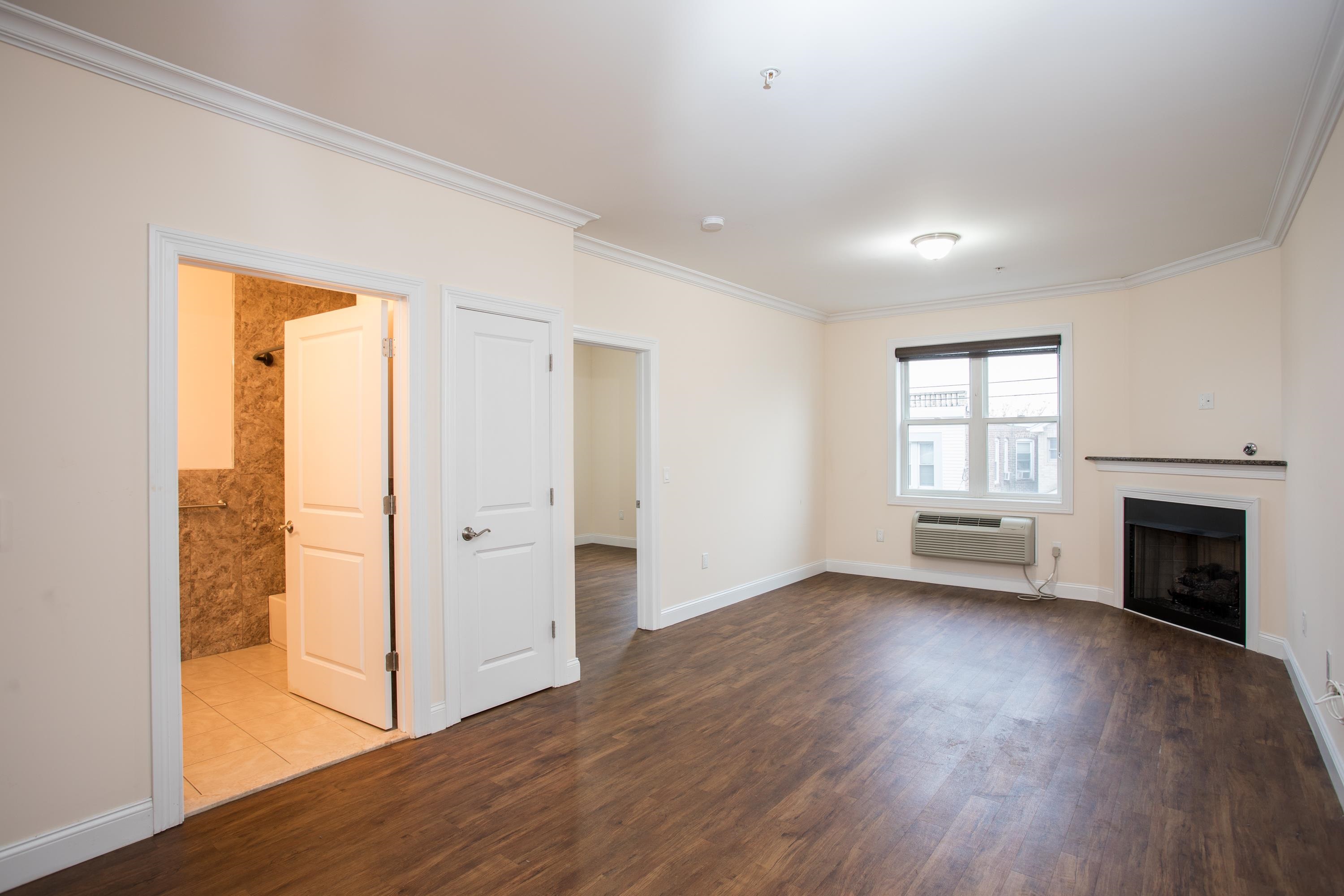 6111 Fillmore Place, Unit 306 West New York, NJ 07093 - Photo 13 of 27 an empty room with wooden floor fireplace and windows