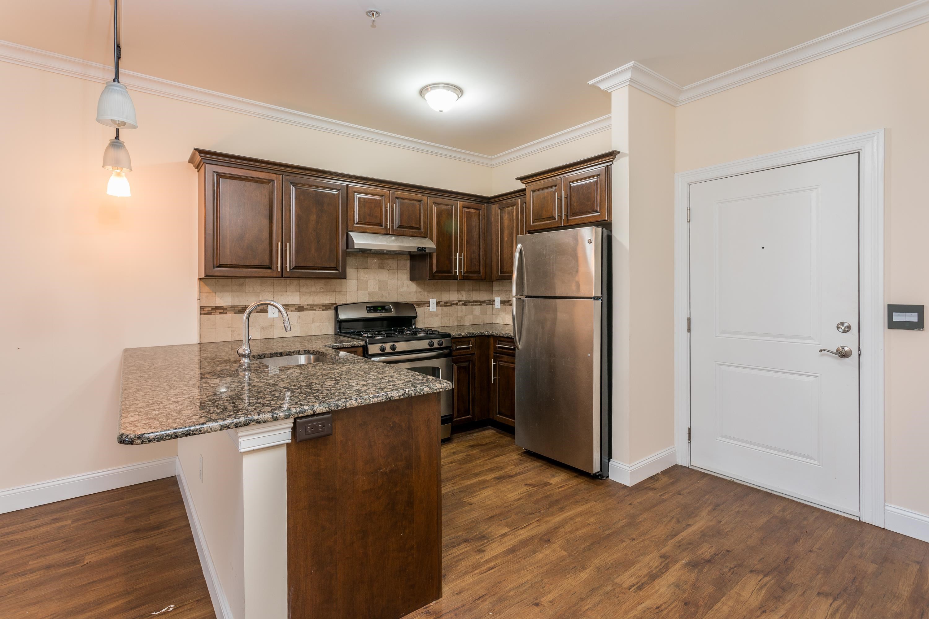 6111 Fillmore Place, Unit 306 West New York, NJ 07093 - Photo 7 of 27 a kitchen with kitchen island a counter top space stainless steel appliances and cabinets