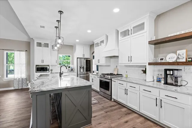 a large kitchen with granite countertop a sink a counter space appliances and cabinets