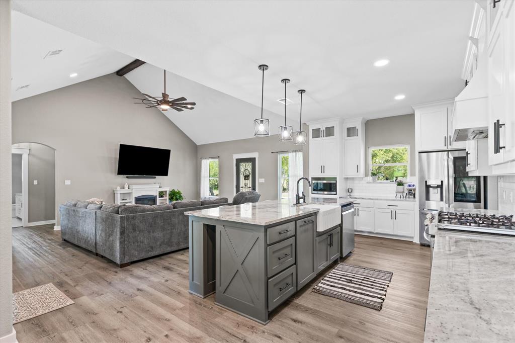 710 Valek Road Ennis, TX 75119 - Photo 19 of 40 a open kitchen with stainless steel appliances kitchen island granite countertop a stove top oven a sink dishwasher a dining table and chairs with wooden floor