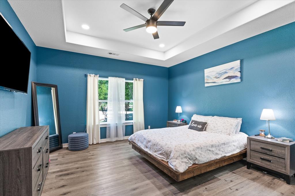 710 Valek Road Ennis, TX 75119 - Photo 23 of 40 a bedroom with a large bed and a flat tv screen on dresser