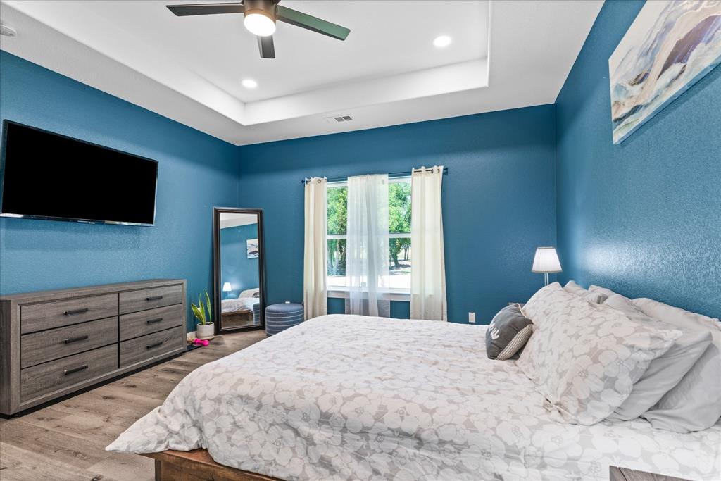 710 Valek Road Ennis, TX 75119 - Photo 24 of 40 a bedroom with a large bed and a flat screen tv