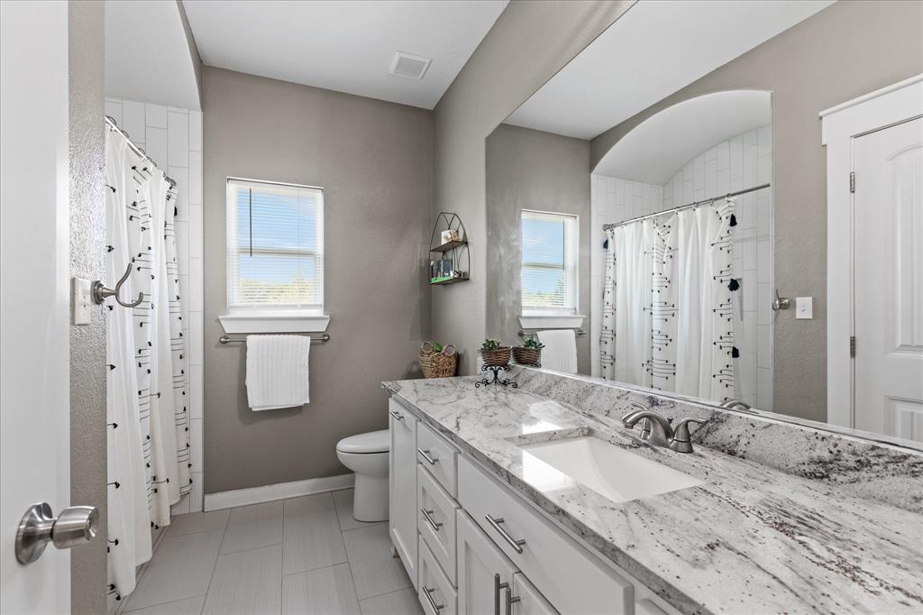 710 Valek Road Ennis, TX 75119 - Photo 32 of 40 a bathroom with a granite countertop sink toilet and shower