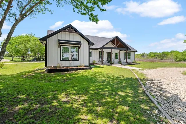 a view of a house with a big yard plants and large trees