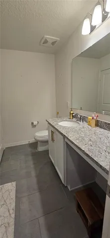a bathroom with a granite countertop sink a toilet and a mirror