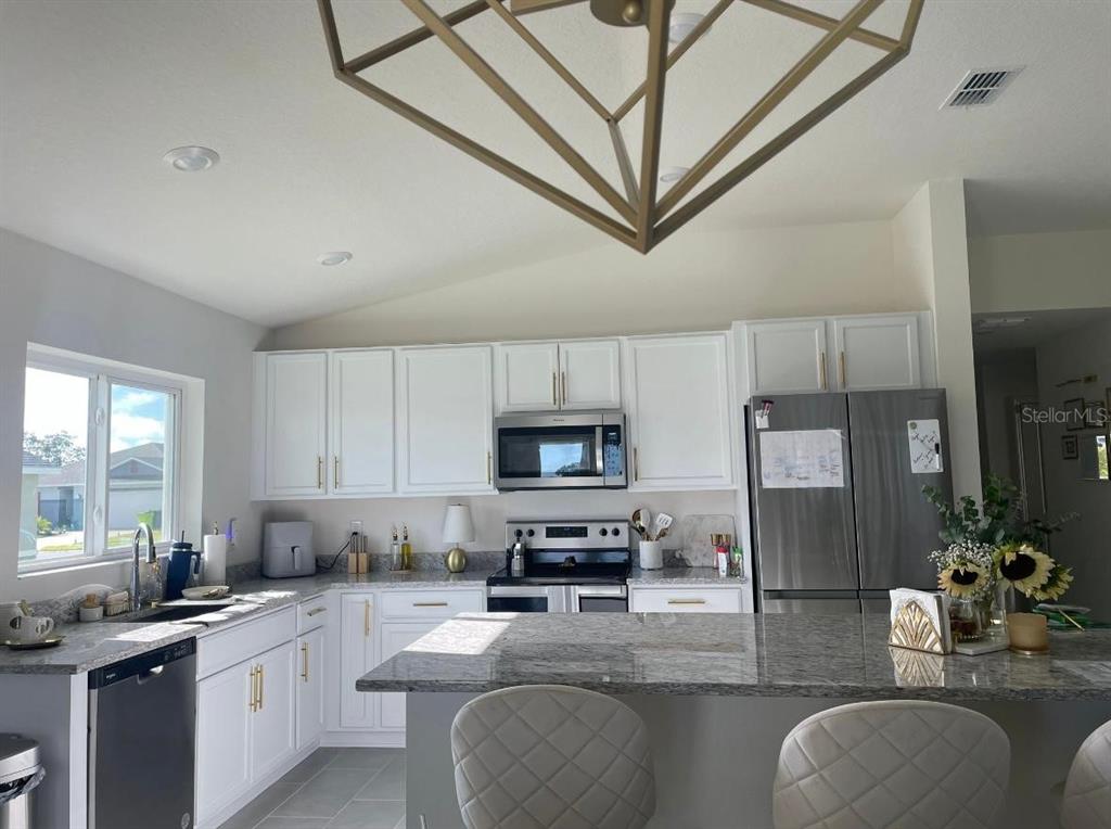 1446 Geranium Drive Mascotte, FL 34753 - Photo 6 of 24 a kitchen with stainless steel appliances granite countertop a stove refrigerator sink and cabinets