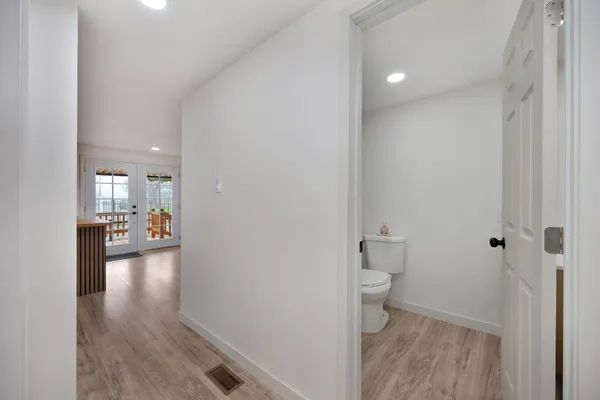 a view of a hallway with wooden floor and a bathroom