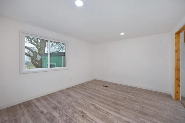 an empty room with wooden floor and windows
