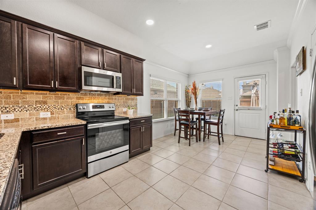3010 Rosemount Lane Forney, TX 75126 - Photo 10 of 33 a kitchen with stainless steel appliances granite countertop a stove top oven a sink dishwasher a dining table and chairs