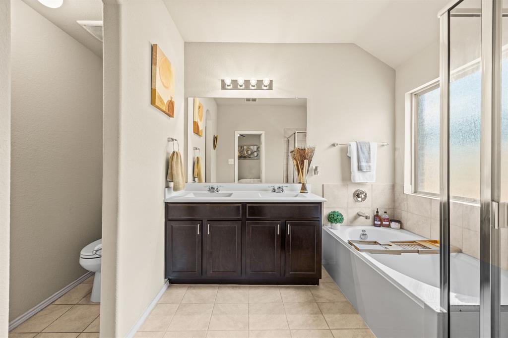 3010 Rosemount Lane Forney, TX 75126 - Photo 18 of 33 a bathroom with a granite countertop sink a large mirror a bathtub and shower