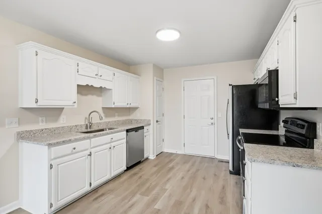 a kitchen with a sink dishwasher a refrigerator and white cabinets