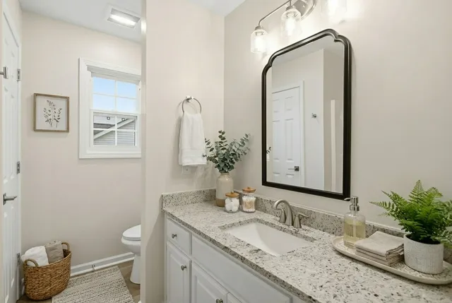 a bathroom with a granite countertop sink a toilet and mirror