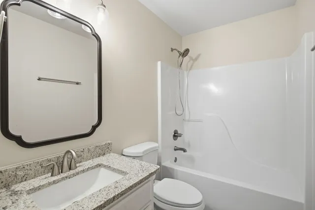 a bathroom with a granite countertop sink toilet and shower