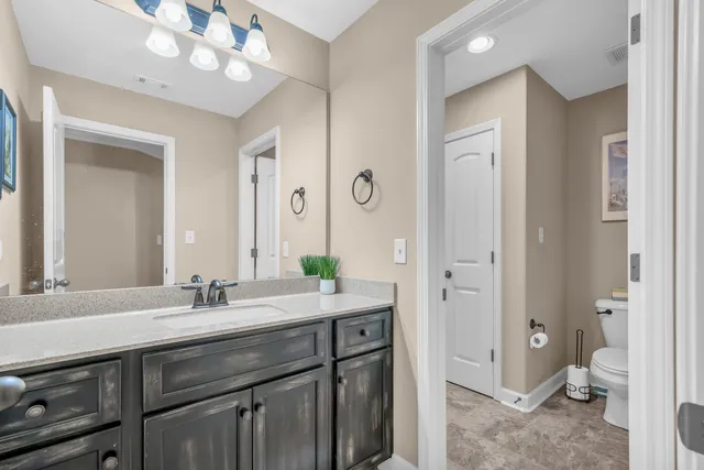 a spacious bathroom with a granite countertop sink a toilet and a mirror
