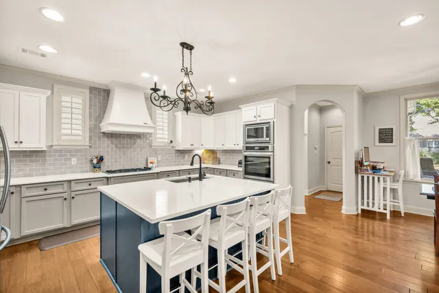 a kitchen with stainless steel appliances a dining table chairs and wooden floor