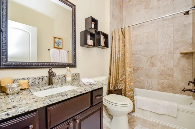 a bathroom with a granite countertop sink toilet and shower