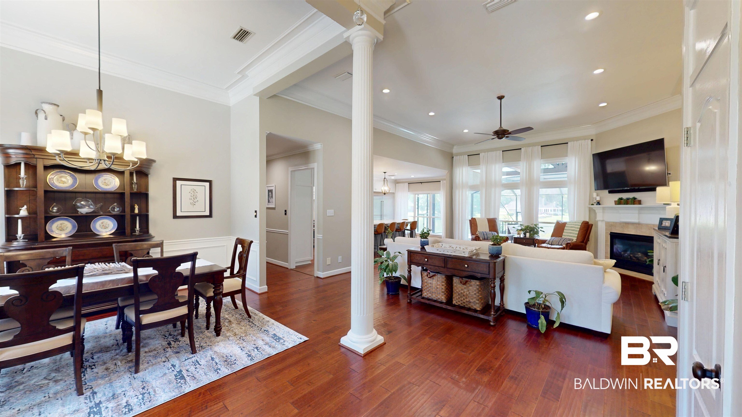 8775 Dawes Lake Road North Mobile, AL 36619 - Photo 18 of 59 Dining room featuring ornate columns, a ceiling fan, dark wood finished floors, crown molding, and a glass covered fireplace