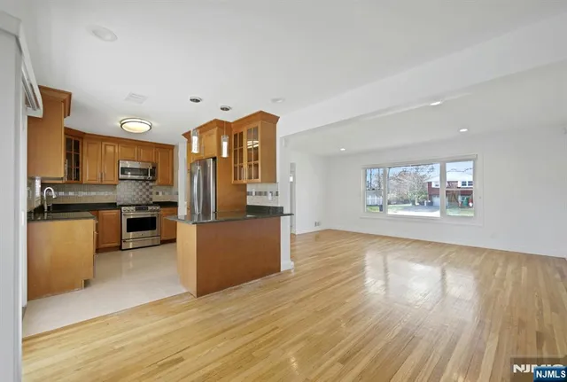 a large kitchen with stainless steel appliances wooden floor and a large window