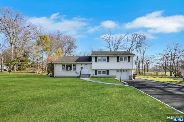 a front view of a house with a garden and trees