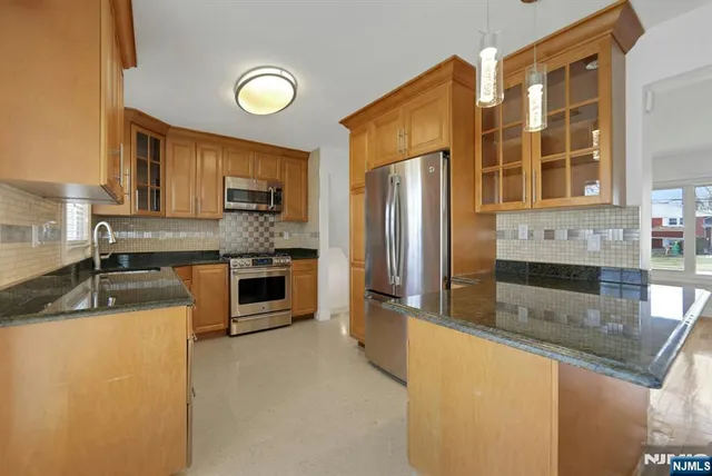 a kitchen with stainless steel appliances granite countertop a sink a stove and a refrigerator