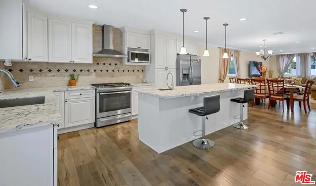 a kitchen with stainless steel appliances granite countertop a stove a sink a oven a dining table and chairs