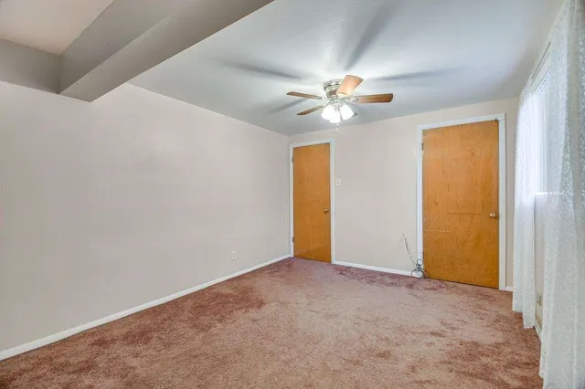 an empty room with a ceiling fan and a window